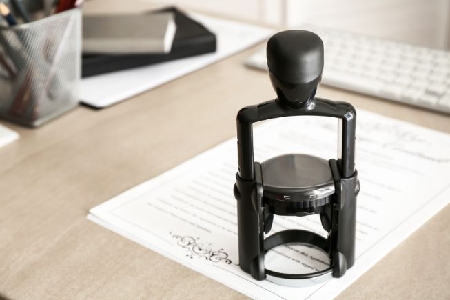 Stock image of a notary stamp on top of a generic, official-looking document on a desk.